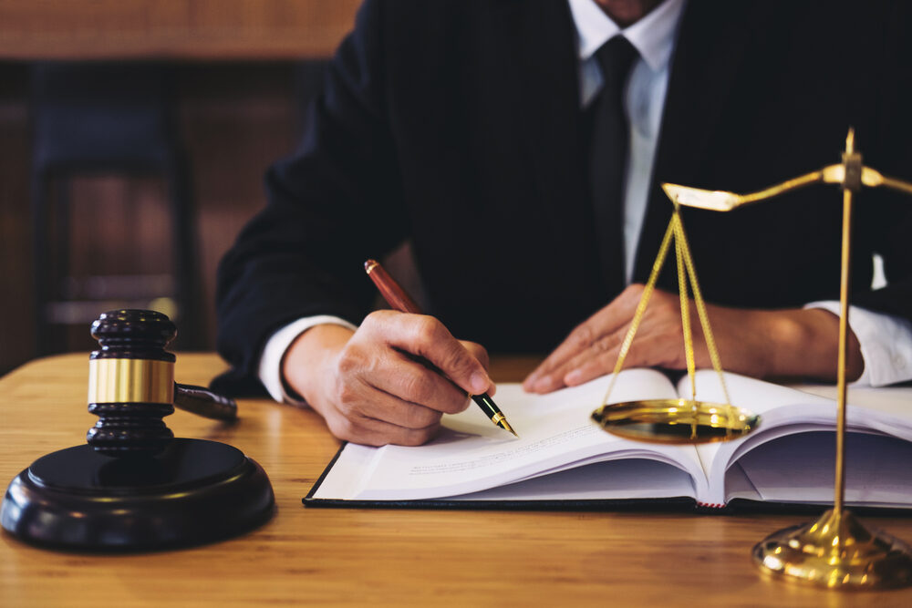 Streamlining Disability Claims: SSA Revises Past Work Evaluation Criteria attorney at desk writing a document with a gavel and scales of justice in the foreground
