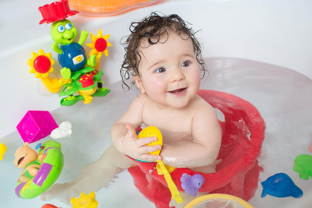 Study: Over 100 Chemicals of Concern in Children’s Toys baby sitting in water in a bath and playing with toys.