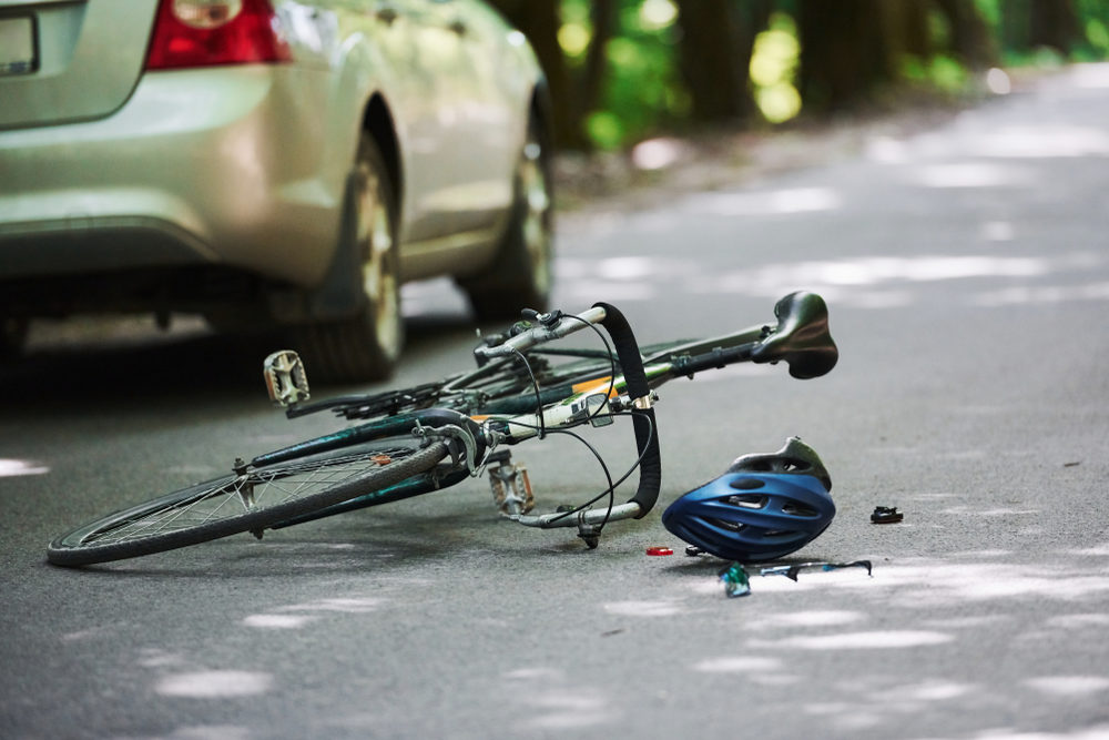 Why Do Hit and Run Drivers Flee the Scene? Bicycle and silver colored car accident on the road at forest at daytime.