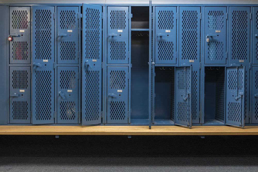Miami-Dade Private School Teacher, Bryant Caniz-Segovia Accused of Sexually Abusing 14-Year-Old Student at Hope Academy Blue metal cage lockers with a wood bench in a locker room with some doors open and some doors closed