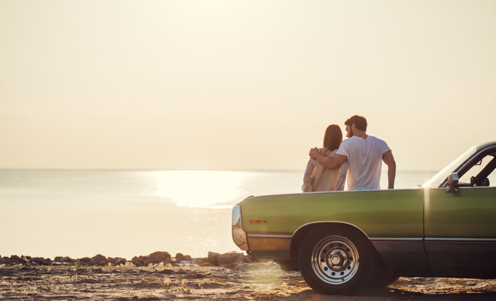 What to Do After an Out-of-State Car Accident in North Carolina couple is standing near green retro car on the beach