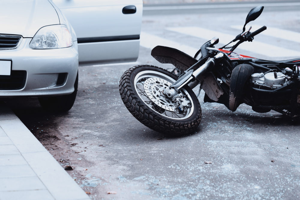 Virginia Motorcycle Accidents and Ways to Prevent Severe Personal Injuries Motorcycle lying on the road and car standing with open door after a collision