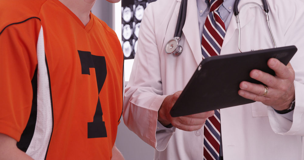 Sexual abuse Lawsuit Filed Against Lancaster, PA Sports Physician, Dr. William Vollmar Male doctor looking at tablet with male athlete in office