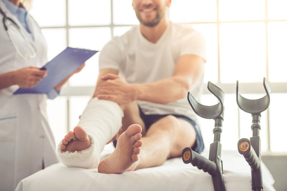 Just How Long Does a Permanent Injury Last? female doctor with a male patient with a broken leg on an exam table in office