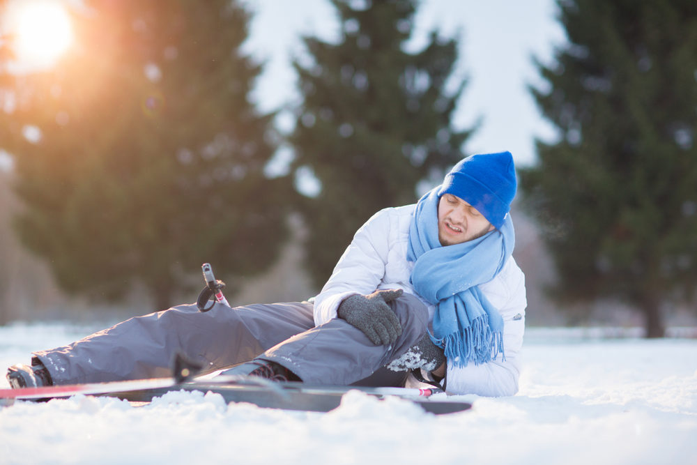 Pursuing Legal Action for Skiing or Snowmobile Accident Injuries Young sportsman rubbing his hit knee after crash in snow during ski training
