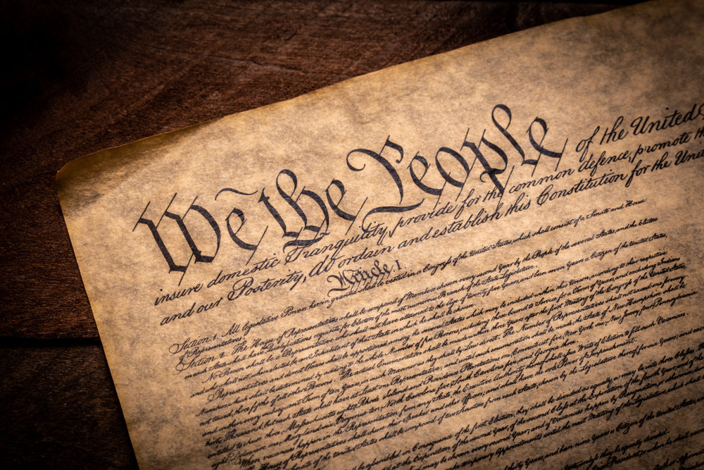 2nd and the 7th Amendment A copy of the Constitution of the United Sates of American on a wooden background