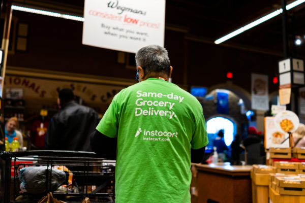 Wegmans grocery store interior with Instacart man worker and sign on shirt for same-day delivery