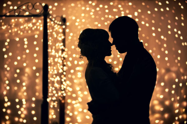 hugs lovers in silhouette against the background of garlands of lights