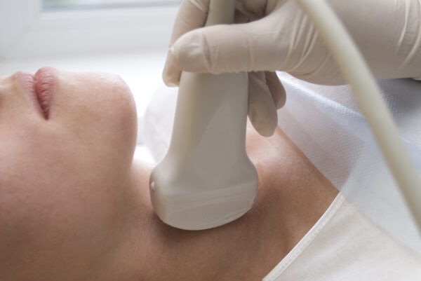 closeup of an endocrinologist scanning a woman's thyroid