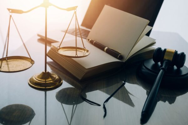 scales of justice, notepad and pen, gavel, and laptop on a lawyer's desk closeup